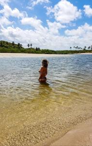 a young child sitting in the water on a beach at casa de praia a beira mar in Campina +7 photos