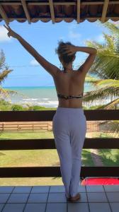 a woman standing in front of a window looking at the ocean at casa de praia a beira mar in Campina