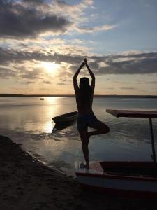 a person doing a yoga pose on a boat on the beach at casa de praia a beira mar in Campina