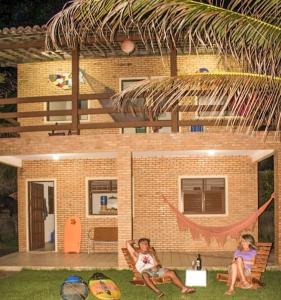 two children laying on the grass in front of a house at casa de praia a beira mar in Campina