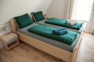 two beds with green pillows on them in a bedroom at Heerlijk genieten. in Hoogersmilde