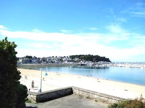 a beach with people on the sand and the water at La Cabane - Petit studio mansardé - Plage 50m - Rue gratuite in Saint Malo