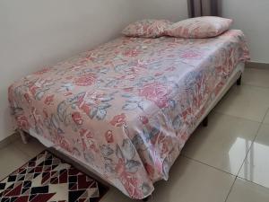 uma cama com uma colcha rosa e almofadas em Apartamento Vila Aconchego Vermelho em Salvador