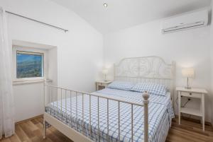 a white bedroom with a bed and a window at House Bajota with terrace and sea view in Beli
