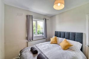 um quarto com uma cama com almofadas amarelas e uma janela em Guest Homes - Birches Barn em Wolverhampton