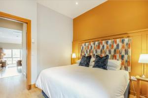 a bedroom with a large white bed with blue pillows at Woodside Apartments in St. Andrews