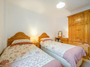 a bedroom with two beds and a wooden cabinet at Little Springfield in Hayle