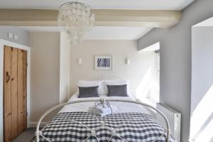 Coombers Mead Cottage في تيتبري: غرفة نوم بسرير وثريا