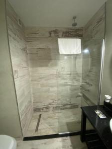 y baño con ducha y puerta de cristal. en Glo apart hotel en Cañuelas