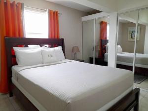 a bedroom with a large white bed with orange curtains at Choose To Be Happy at Brompton Estates - One and Two Bedroom with Pool in Kingston