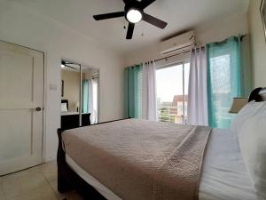 Schlafzimmer mit einem Bett, einem Deckenventilator und einem Fenster in der Unterkunft Choose To Be Happy at Brompton Estates - One and Two Bedroom with Pool in Kingston