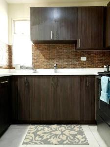 a kitchen with wooden cabinets and a sink and a window at Choose To Be Happy at Brompton Estates - One and Two Bedroom with Pool in Kingston
