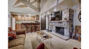 a living room with a couch and a stone fireplace at Updated 2Br Plus Loft Condo on Shuttle Route! Sleeps 8 & Kids Ski Free condo in Montezuma