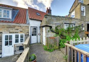 a stone house with a white door and a fence at Storm Cottage in Robin Hood's Bay