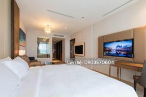1 dormitorio con 1 cama blanca grande y TV en Panorama Nha Trang Apartment Sea View - Căn Hộ Hướng Biển, en Nha Trang