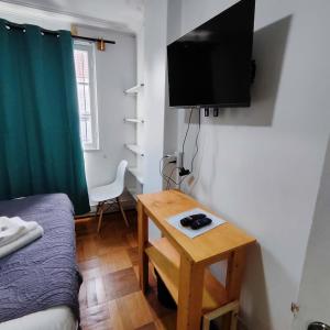 a small room with a bed and a table with a television at HOSTAL SUZI in Santiago