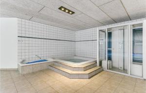 a bathroom with a bath tub and a shower at Cozy Home In Løkken With Kitchen in Lønstrup
