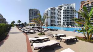 a row of lounge chairs next to a pool and buildings at Edelweiss Resort Luxury Studio Apartment in Iskele