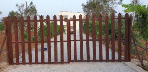 a wooden gate in front of a house at la villa con terrazza sul mare di Paf in Marina di Mancaversa