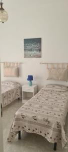 a bedroom with two beds and a table with a lamp at la villa con terrazza sul mare di Paf in Marina di Mancaversa