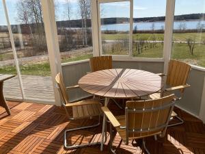 uma mesa e cadeiras num alpendre com uma mesa e janelas em Villa med sjöutsikt em Fors