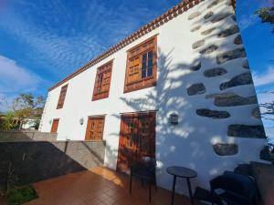 uma casa branca com janelas de madeira e dois bancos em Hotel Rural Casablanca em Los Realejos