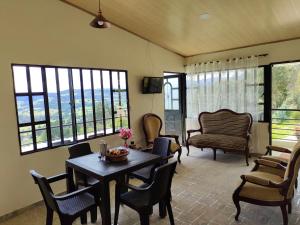 a living room with a table and chairs and windows at Posada Campestre Macadamia in Paipa