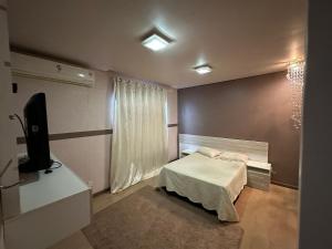 a small bedroom with a bed and a television at Pousada Residencial - PVH in Porto Velho