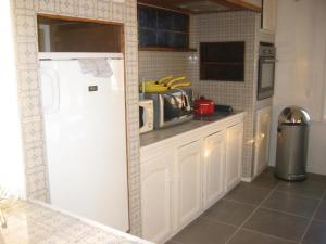 een keuken met een witte koelkast en een magnetron bij Les Racines de la Vie Rurale in Ledringhem