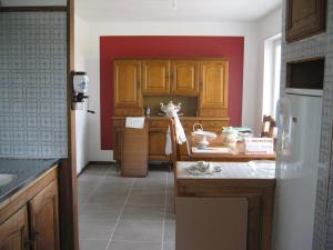 een keuken met houten kasten en een rode muur bij Les Racines de la Vie Rurale in Ledringhem