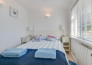 1 dormitorio con cama con sábanas azules y ventana en Cliff Top Cottage en Porthleven