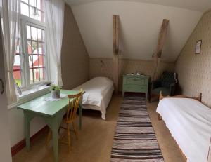 Habitación con 2 camas, mesa, mesa y ventana en Medstugans vandrarhem en Duved
