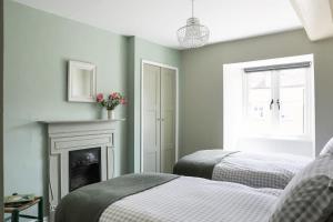a bedroom with two beds and a fireplace at Coombers Mead Cottage in Tetbury