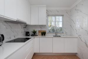 a white kitchen with white cabinets and a window at NEW LISTING - Eden Villas in Vilamoura