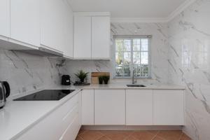 Una cocina blanca con gabinetes blancos y una ventana. en NEW LISTING - Eden Villas, en Vilamoura