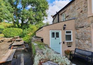 a stone building with a white door and a bench at South View Cottage in Horton in Ribblesdale