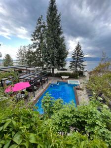 uma piscina com mesas, guarda-sóis e árvores em Villa Dionis em Ohrid