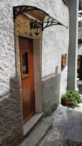 a stone building with a wooden door with a light above it at La Cà Rustica - casa vacanze in Bognanco