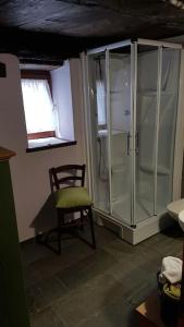 a bathroom with a glass shower and a chair at La Cà Rustica - casa vacanze in Bognanco