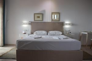 - un lit avec des draps et des oreillers blancs dans une chambre dans l'établissement Alexandros Apartments & Αλέξανδρος Villas, à Kalamaki Messinia