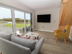 a living room with a couch and a tv at Bwthyn Cae'r Efail in Bodewryd