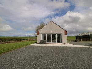 a small house on a gravel driveway with a field at Bwthyn Cae'r Efail in Bodewryd