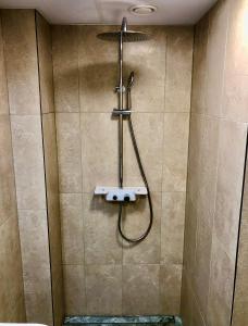 una ducha con una manguera pegada a la pared en Kohtu Apartment Cozy en Kuressaare