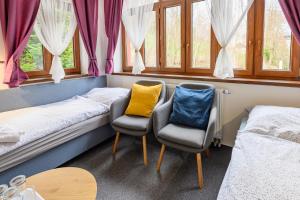 2 camas y 2 sillas en una habitación con ventanas en Penzion Zámeček, en Janske Lazne