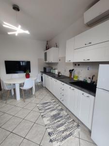 - une cuisine avec des placards blancs, une table, une table et un tapis dans l'établissement Cerro Flat, à Cerro Maggiore