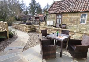 a patio with a table and chairs and a stone wall at Smugglers Cove Cottage in Ravenscar