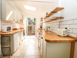 a kitchen with white cabinets and wooden counter tops at 8 Melinda Cottage in Cromer