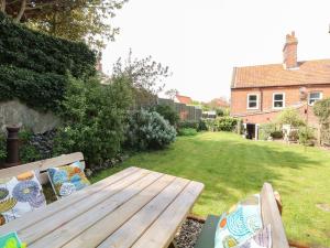 a wooden bench sitting in a yard next to a garden at 8 Melinda Cottage in Cromer