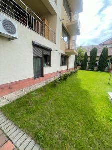um quintal de um edifício com um relvado verde em Zimbrului Apartment em Bistrita