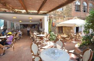 un patio esterno con tavoli, sedie e ombrellone di Hotel Stella Maris a Capoliveri